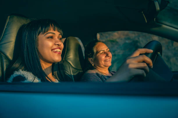 Happy young woman driving a car with her mother. An Asian/Indian happy young woman driving a car with her senior retired mother. asian mother talking with daughter stock pictures, royalty-free photos & images