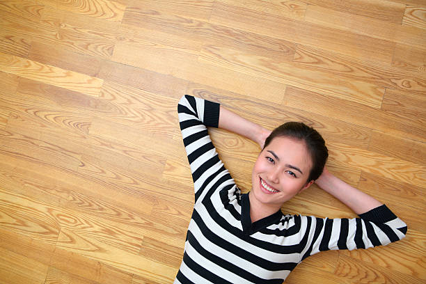 happy young woman lying on wooden floor stock photo