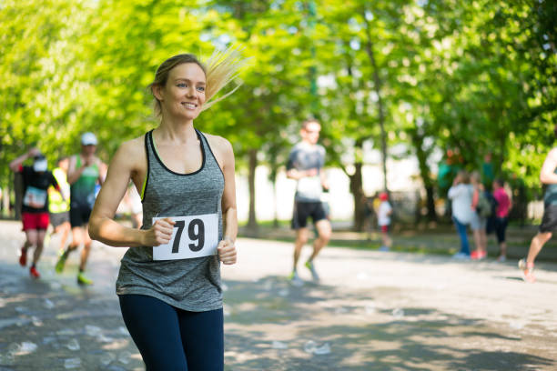 happy young woman running marathon on sunny day in spring smiling woman outdoors in spring running marathon sports event, background blurred, copy space marathon stock pictures, royalty-free photos & images