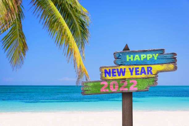 Hapy new year 2022 written on direction signs, tropical beach background, travel and tourism greeting card stock photo