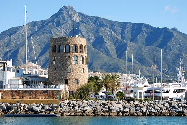 Harbour entrance, Puerto Banus, Spain. "Harbour entrance with the watchtower to the left and La Concha mountain to the rear, Puerto Banus, Marbella, Costa del Sol, Malaga Province, Andalusia, Spain, Western Europe." marbella stock pictures, royalty-free photos & images