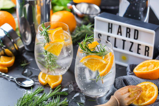 Hard seltzer cocktail with orange, rosemary and bartenders accessories stock photo