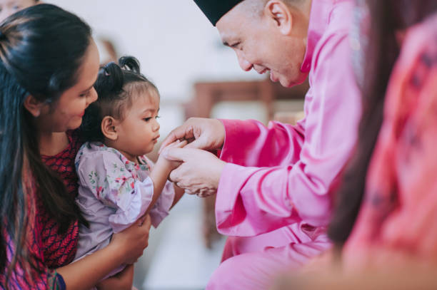 Hari raya malay muslim baby girl together with her mother and grandparent in Hari Raya Aidilfitri / Eid-Ul-Fitr celebration in living room  idul fitri stock pictures, royalty-free photos & images