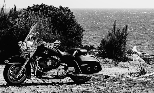 Cascais, Portugal - May 7, 2020: Harley Davidson bike parked with owner sleeping at far end - monochrome