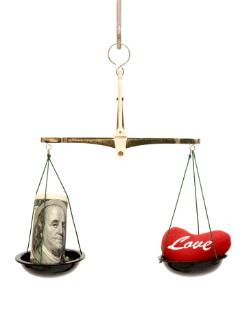 A bowl with heart is in balance with a bowl with money.