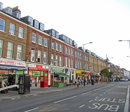 London, UK - 16th April 2014: Shops, vehicles and unidentified people on Harrow road in north west London