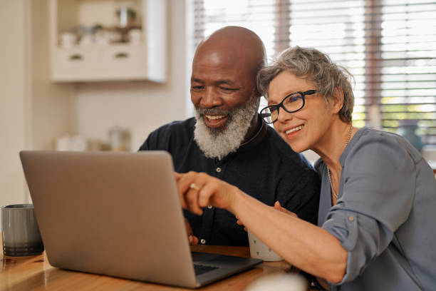 Have a look at that over there Cropped shot of an affectionate and happy senior couple using a laptop while relaxing together at home laptop couple stock pictures, royalty-free photos & images