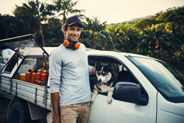 Have you met my colleague? Portrait of a happy landscaper petting his dog while standing next to his vehicle car lifestyle stock pictures, royalty-free photos & images