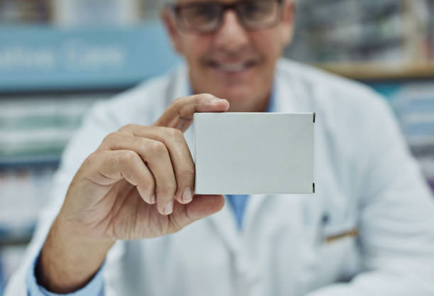 Have you tried this new brand? Shot of a mature pharmacist holding a blank medicinal box in a chemist dose photos stock pictures, royalty-free photos & images