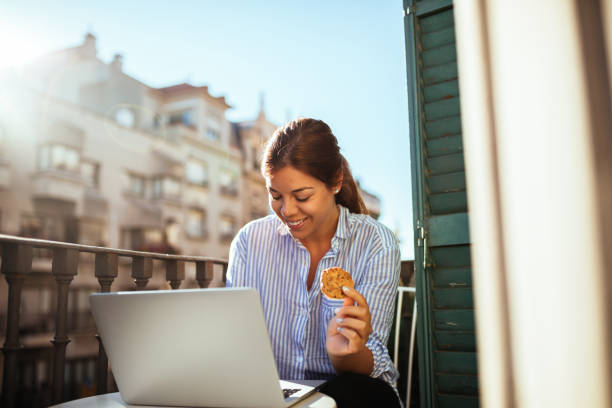 Having a snack Beautiful woman having snack on a balcony. free video chat with women stock pictures, royalty-free photos & images
