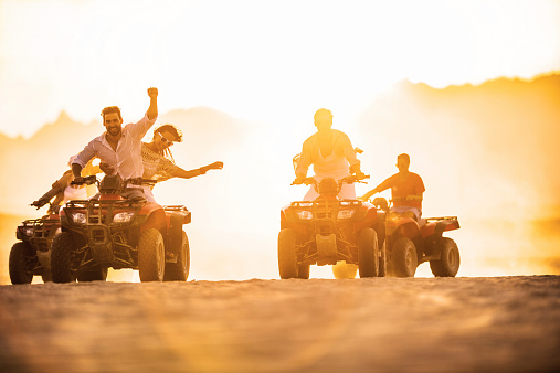 Young people driving quad bikes and having fun in the desert.