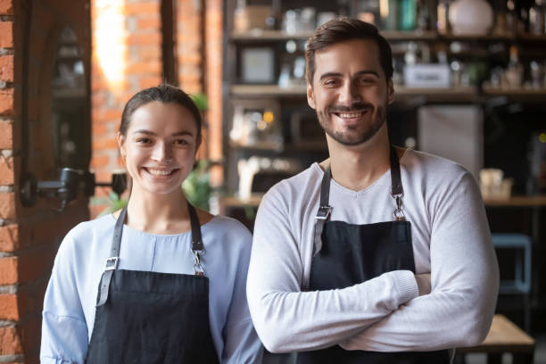 head shot portrait of coffeehouse workers, smiling waiter and waitress - her happy place is with her team imagens e fotografias de stock