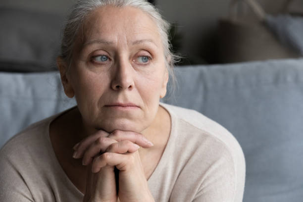 Head shot thoughtful old grandmother suffering from loneliness. stock photo
