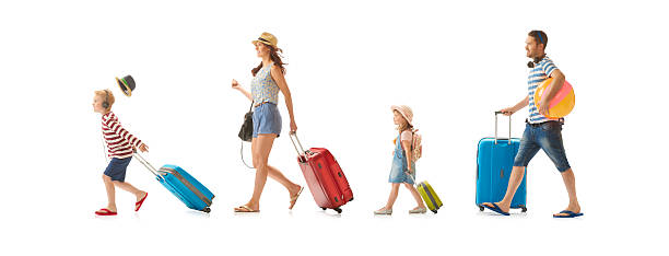a young family march across the shot pulling their suitcases as they look like they're heading for the airport , or hotel. the little boy at the front is rushing so much his hat has blown off . The family consists of mum , dad, daughter and son .