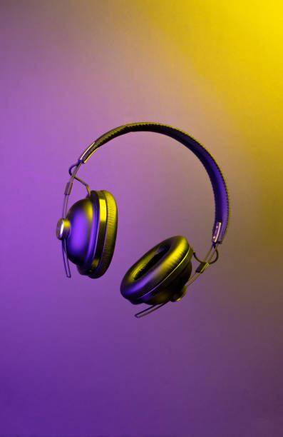 headphone levitating on multi-colored illuminated background. Music streaming, wireless, podcast. stock photo
