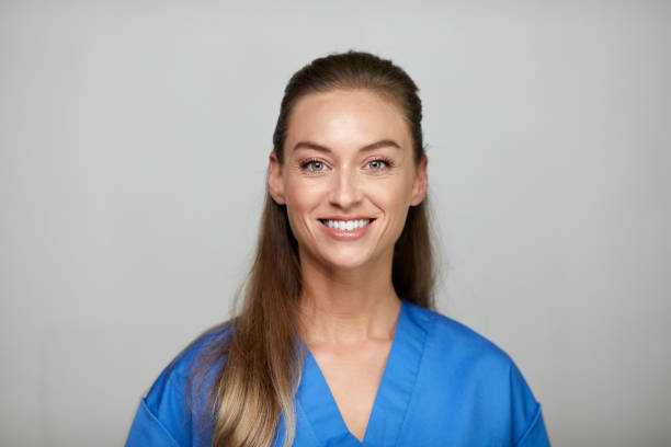 Headshot of a nurse smiling and looking at the camera. Studio shot of a young woman looking at the camera. nurse face stock pictures, royalty-free photos & images