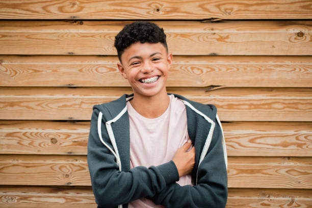 Headshot of a Teenage Boy Headshot of a teenage boy standing, smiling and flowing his arms while looking at the camera. dental braces stock pictures, royalty-free photos & images