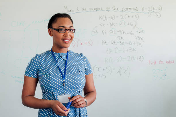 Headshot of Female Teacher Headshot of black female teacher standing in front of whiteboard. british curriculum schools stock pictures, royalty-free photos & images