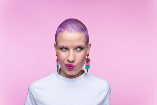 Headshot of woman with short purple hair and rainbow earrings stock photo