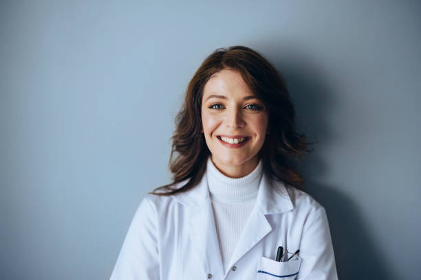 headshot portrait of happy female doctor on a gray wall - doctor wall imagens e fotografias de stock