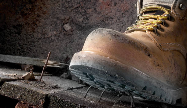 Health and safety Dirty work boots stepping on a nail stock photo