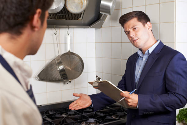 Health Inspector Meeting With Chef In Restaurant Kitchen stock photo