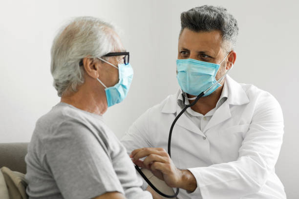 health visitor and a senior man during home visit - médico a examinar paciente imagens e fotografias de stock