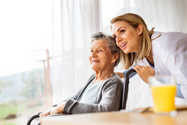 Health visitor and a senior woman during home visit. Health visitor and a senior woman during home visit. A nurse talking to an elderly woman in an wheelchair. Assisted living stock pictures, royalty-free photos & images