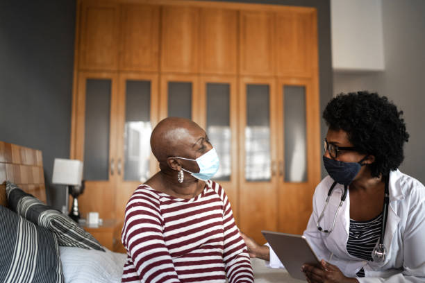 health visitor and a senior woman during nursing home visit - pandemia doença imagens e fotografias de stock