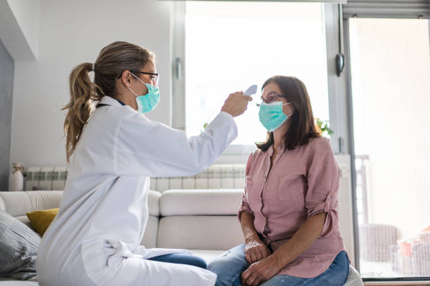 Healthcare worker at home visit Healthcare worker at home visit. Female doctor is checking temperature to senior woman. at home covid test stock pictures, royalty-free photos & images
