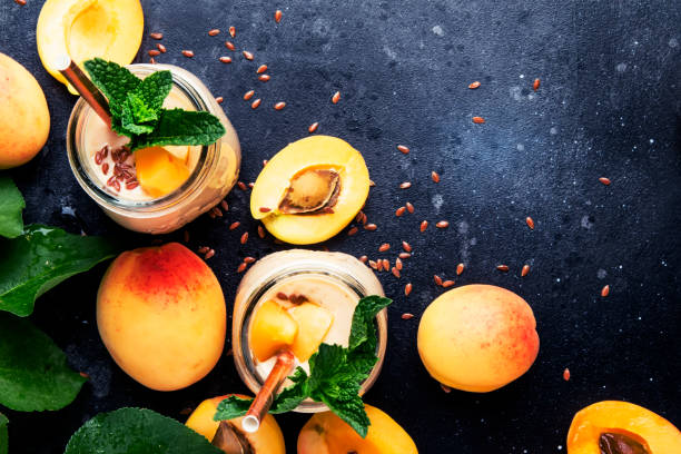 Healthy apricot smoothies in glass bottles Healthy apricot smoothies in glass bottles and fresh fruits, top view peach smoothie stock pictures, royalty-free photos & images