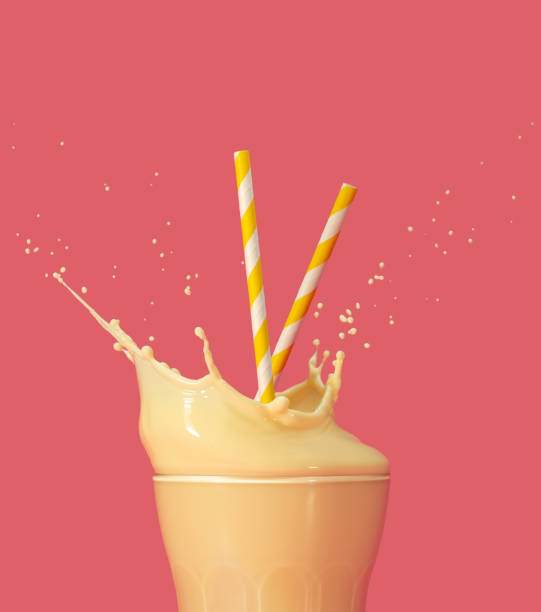 healthy banana or pineapple smoothie splashing on colored background drinking straws into a splashing glass of yellow milkshake on pastel pink background mango smoothie stock pictures, royalty-free photos & images