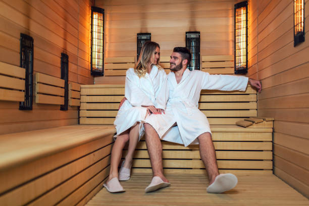 Healthy beautiful couple relaxing in sauna during wellness weekend Healthy beautiful couple relaxing in infrared sauna during wellness weekend infrared stock pictures, royalty-free photos & images