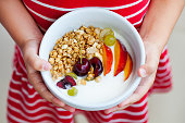 Healthy breakfast. Fresh granola, muesli with yogurt, fruits and berries in little girl's hands