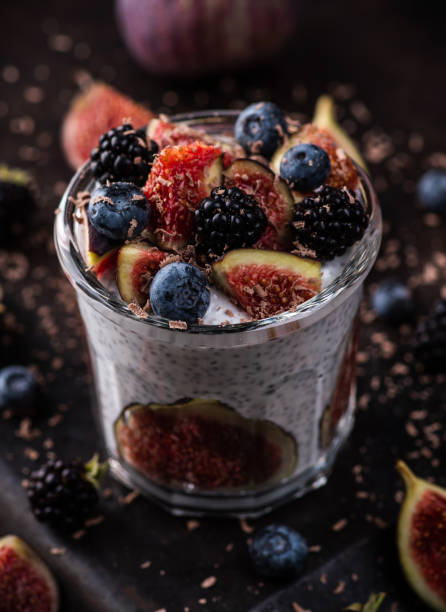 Healthy chia pudding with figs and dark berries in glass on the rustic background. Selective focus. Shallow depth of field. stock photo