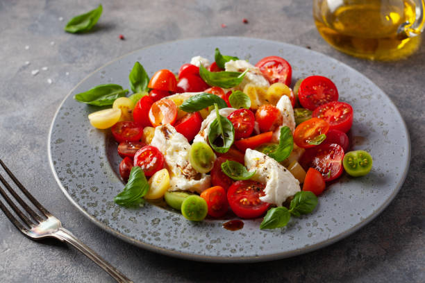 healthy colorful tomato mozzarella basil salad with balsamic vinegar dressing stock photo