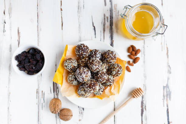 healthy energy organic bites with nuts, dates, honey and sesame in a plate on a light wooden background. stock photo