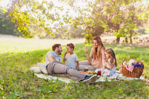 Healthy Family enjoying summer picnic in the nature Fruits of summer enjoyed by a young beautiful family picnic stock pictures, royalty-free photos & images