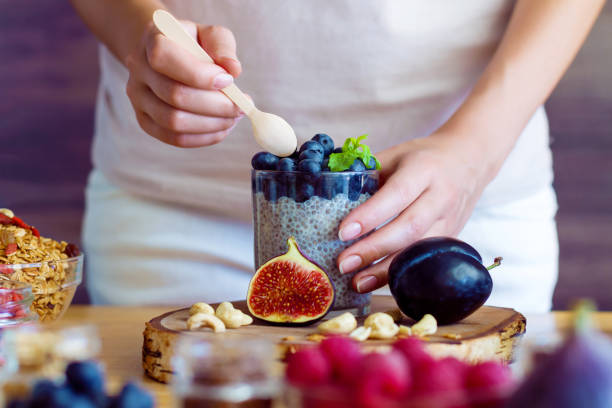 Healthy fitness food for breakfast Female hands are preparing yogurt with chia and blueberries for good digestion, functioning of gastrointestinal tract. Summer berries, nuts, fruits, dairy products on table. Healthy food concept. human digestive system photos stock pictures, royalty-free photos & images