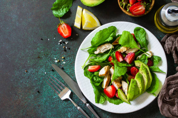 Healthy food, diet lunch menu concept, ketogenic diet and paleodiet. Summer salad with strawberries, grilled chicken and avocado on a stone table. Top view flat lay. Copy space. stock photo