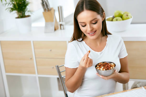 gezonde voeding. gelukkige vrouw eten noten - amandel noot stockfoto's en -beelden