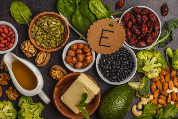 Healthy food nutrition dieting concept. Assortment of high vitamin E sources. Oil, nuts, avocado, butter, healthy fats, rose hips, parsley, seeds, spinach. Dark background, top view stock photo