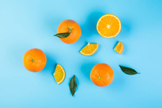 Healthy food. Sliced orange with green leaves on blue background, top view Slices of orange with leaves orange fruit stock pictures, royalty-free photos & images