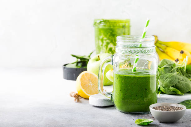 Healthy green smoothie with spinach in glass jar Healthy breakfast with green smoothie in glass jar and ingredients. Detox, diet, healthy, vegetarian food concept with copy space. detox stock pictures, royalty-free photos & images