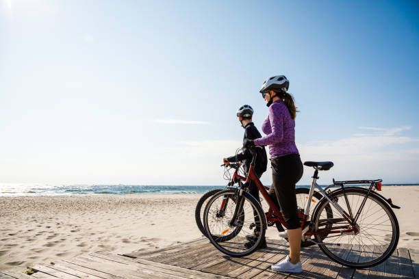 gezonde leefstijl - mensen paardrijden fietsen - fietsen strand stockfoto's en -beelden