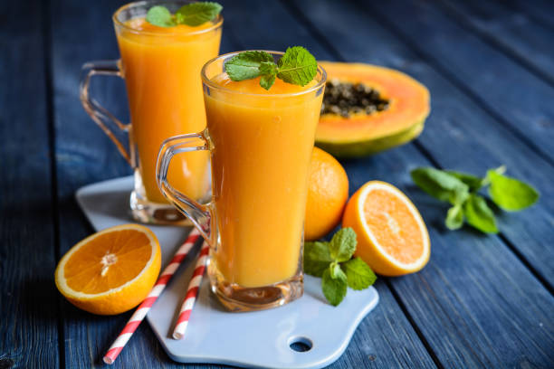Healthy papaya, orange and mango smoothie Healthy papaya, orange and mango smoothie in a glass jar papaya smoothie stock pictures, royalty-free photos & images