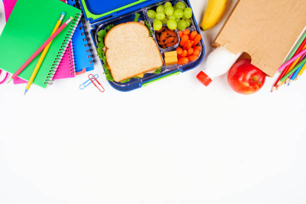 Healthy school lunch with school supplies. Above view top border on a white background. stock photo