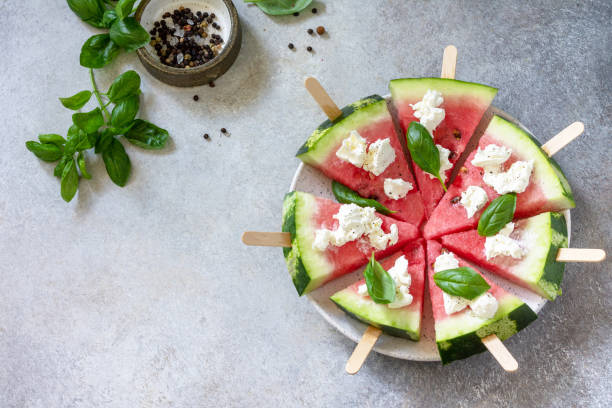 Healthy seasonal dieting and nutrition, summer snack. Watermelon pizza with feta cheese and basil on a gray stone tabletop. Copy space. stock photo