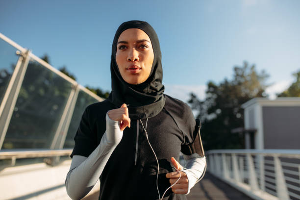 Healthy sporty woman in hijab jogging Healthy sporty woman wearing hijab jogging outdoors in the city. Islamic woman running early in the morning. hijab stock pictures, royalty-free photos & images