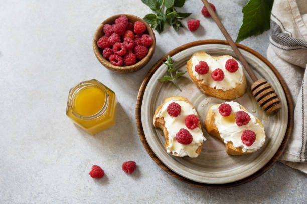 Healthy summer breakfast with sweet sandwiches with ricotta, raspberries and honey on a stone table. Copy space. stock photo